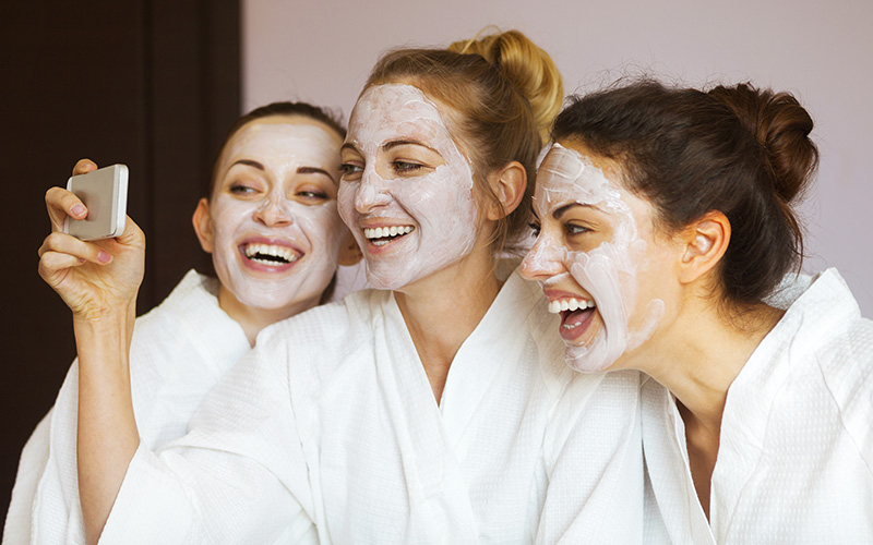 Three young happy women with face masks at spa resort. Frenship
